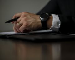 divorce lawyer sat at wooden table with pen and paperwork.