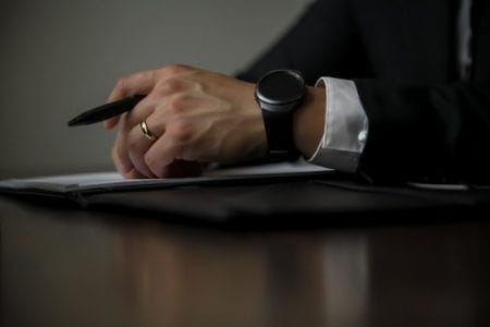divorce lawyer sat at wooden table with pen and paperwork